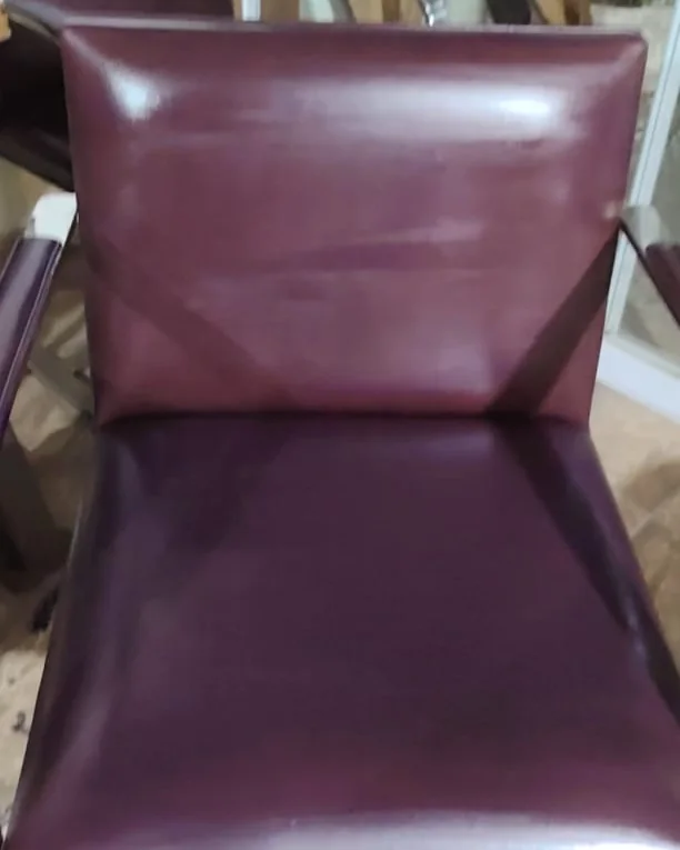 A mesma poltrona de couro bordô após a restauração, com o assento limpo e a cor uniforme