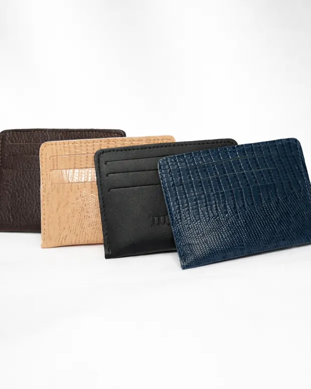 Quatro porta-cartões em couro nas cores marrom, nude, preto e azul