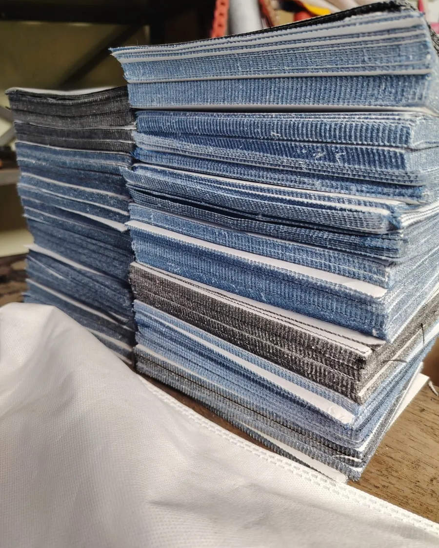 Pilha de peças de jeans cortadas em balancim, empilhadas por tom